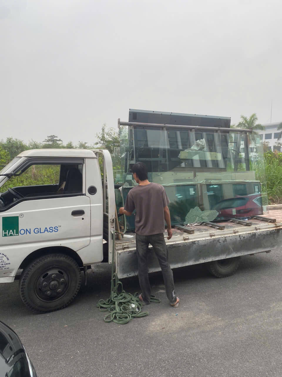 Xe tải Halon Glass chở kính tấm lớn, công nhân đang cố định kính trên thùng xe ngoài trời